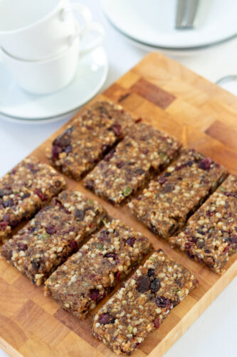 8 healthy fig bars on a chopping board. Cups and saucers in the background.