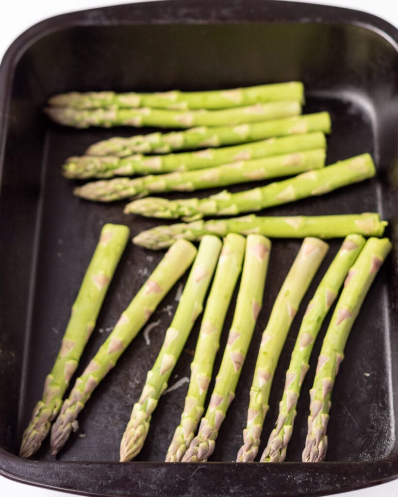 Asparagus spears placed in a roasting tin.