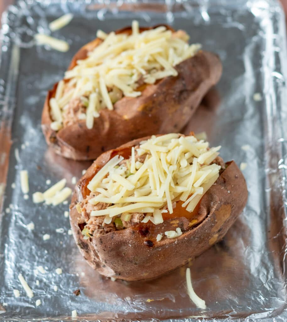 Two baked sweet potatoes cut in half and filled with tuna and cheese filling.