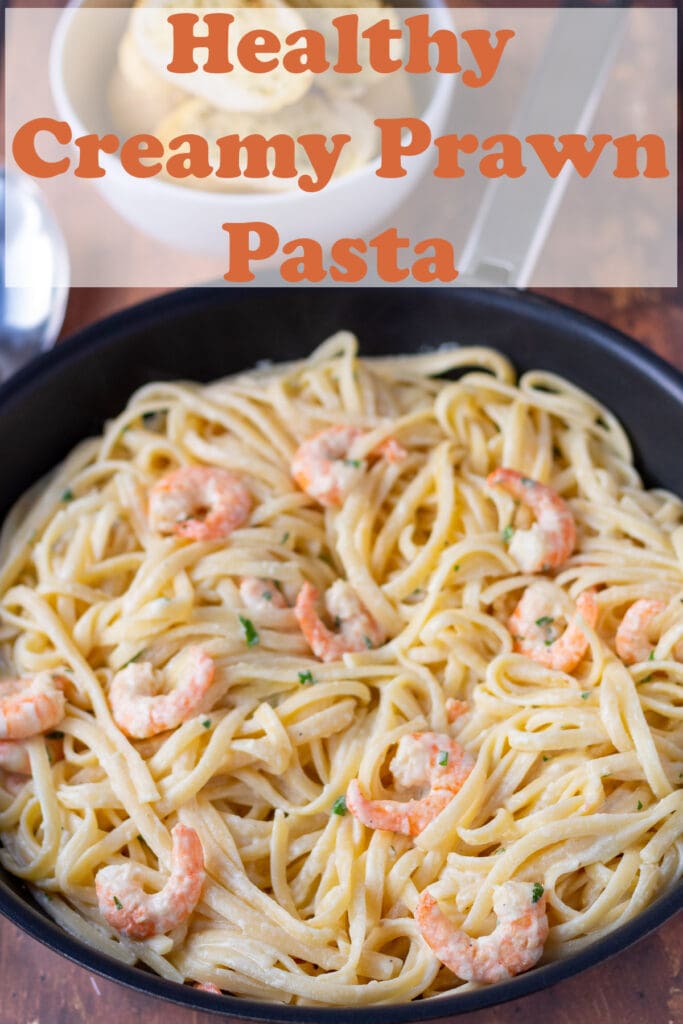 A pan of cooked healthy creamy prawn pasta. Pin title text overlay at top.