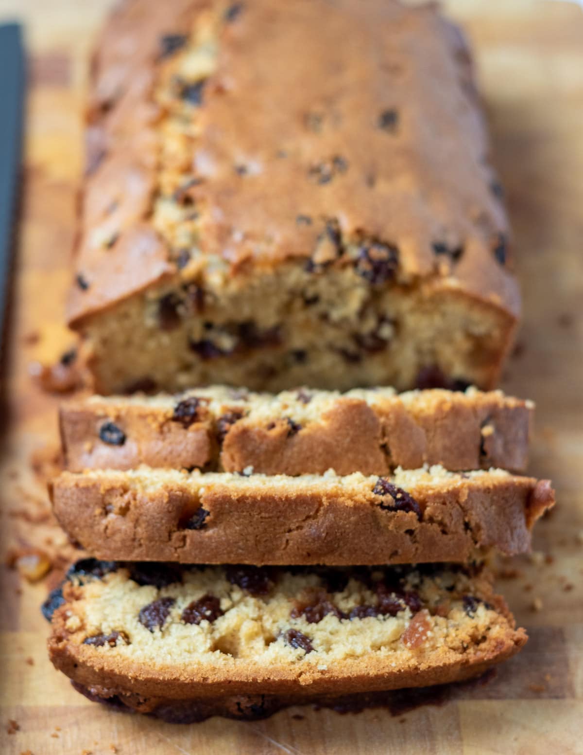 Easy fruit loaf cake on a chopping board with three slices cut off.