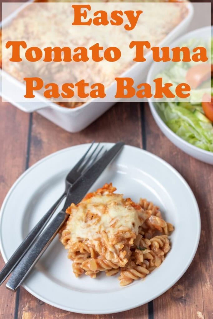 A portion of tomato tuna pasta bake served on a white plate with a knife and fork to the right. Pin title text overlay at top.