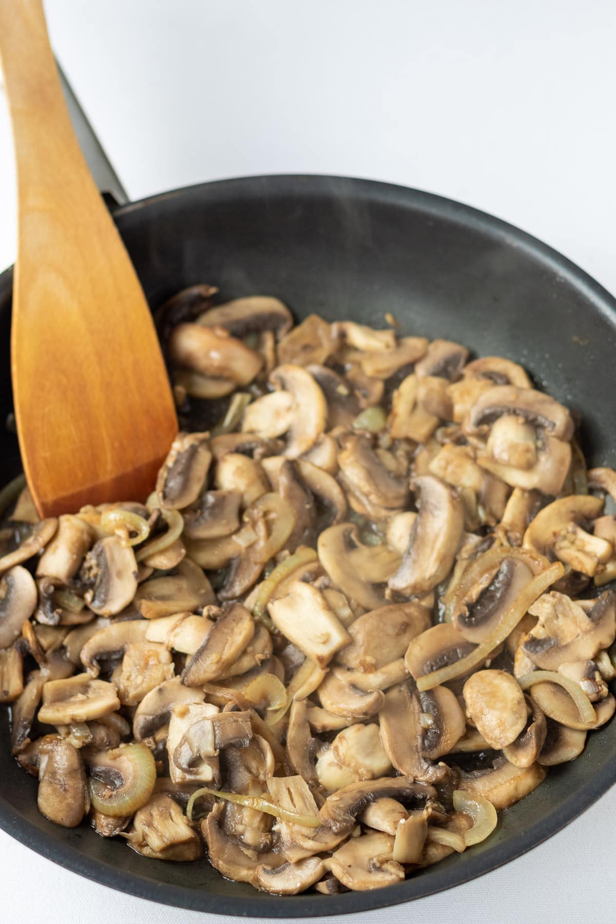 Onion, garlic and mushrooms sautéd in a frying pan.