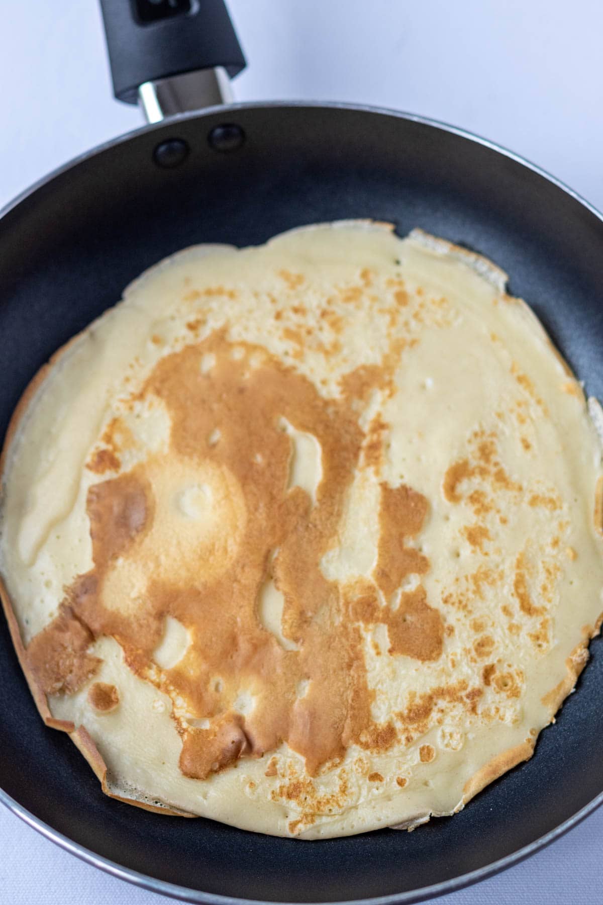 A pancake cooked in a non-stick frying pan.