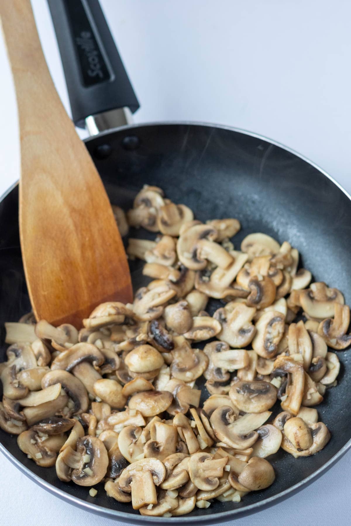 Mushrooms and garlic sautéd in a frying pan.