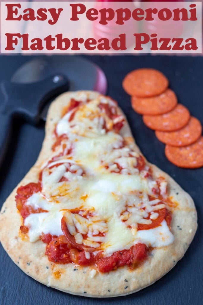 Easy flatbread pepperoni pizza on a black slate. Slices of pepperoni to the right side, pizza cutter to the left. Pin title text overlay at top.