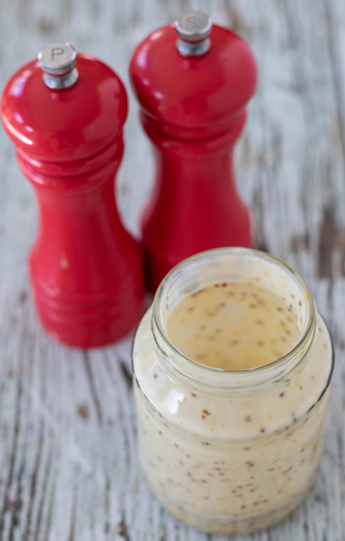 Honey mustard dressing made in a jar. Salt and pepper cellars behind.