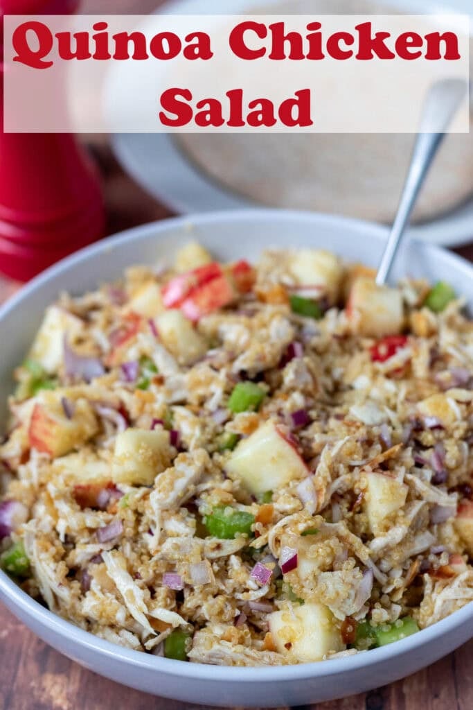 A large bowl of quinoa chicken salad with a serving spoon in. Pin title text overlay at top.