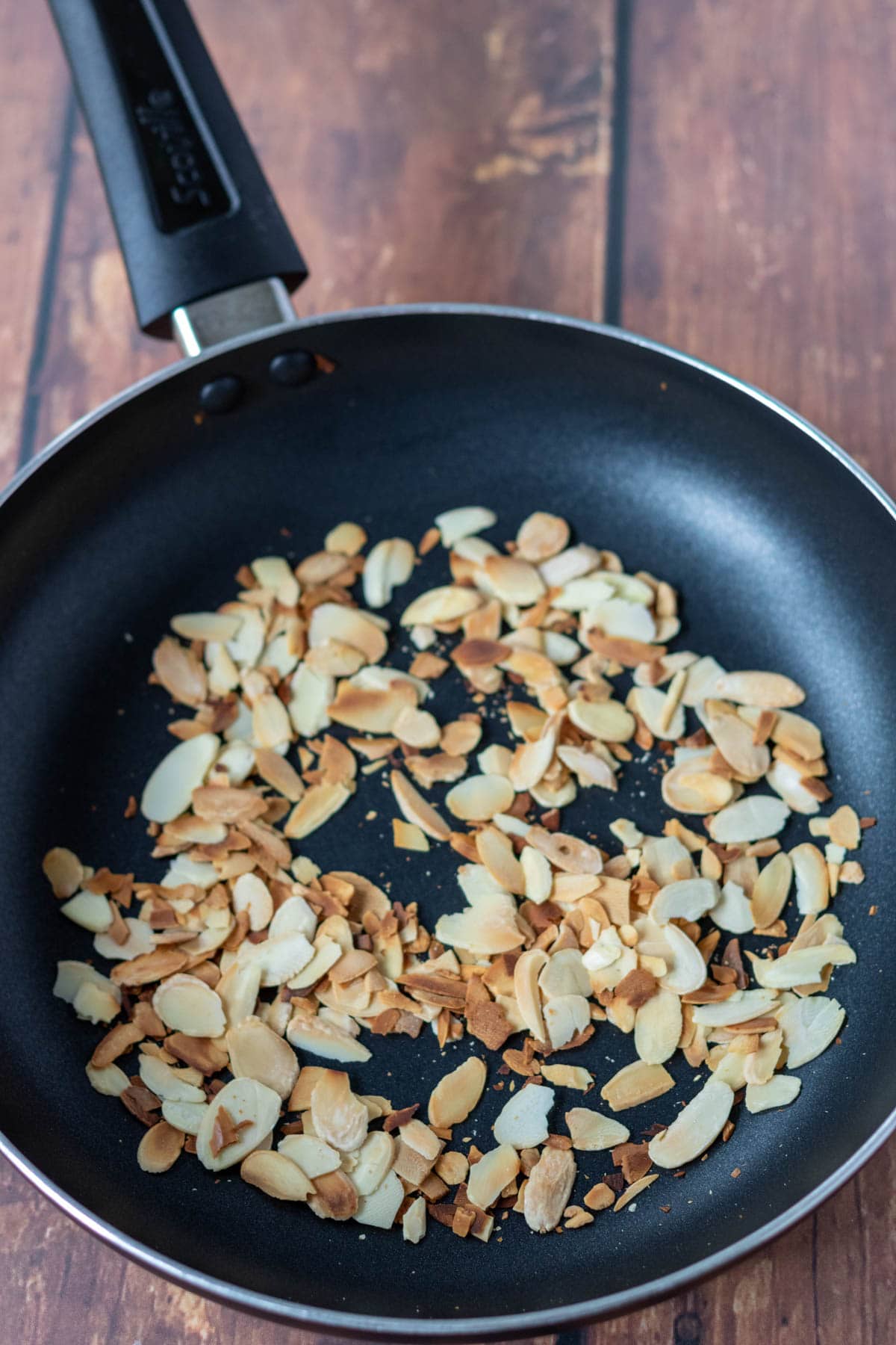 Flaked almonds toasted in a non-stick frying pan.