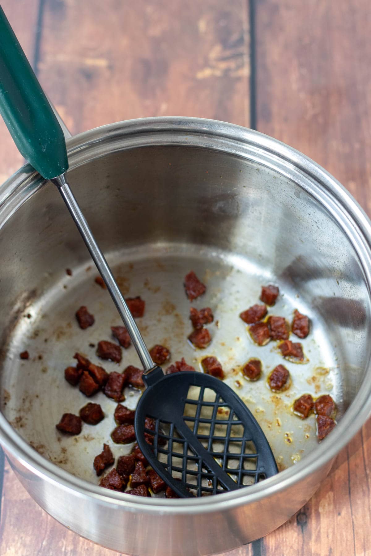 Chopped chorizo stirred and browned in a heated saucepan with a slotted spoon.