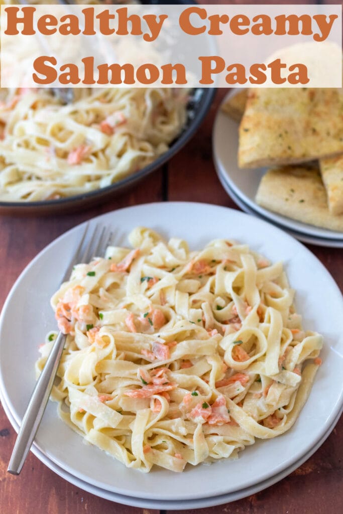 A plate of healthy creamy salmon pasta served. Spoon on side. Pin title text overlay at top.