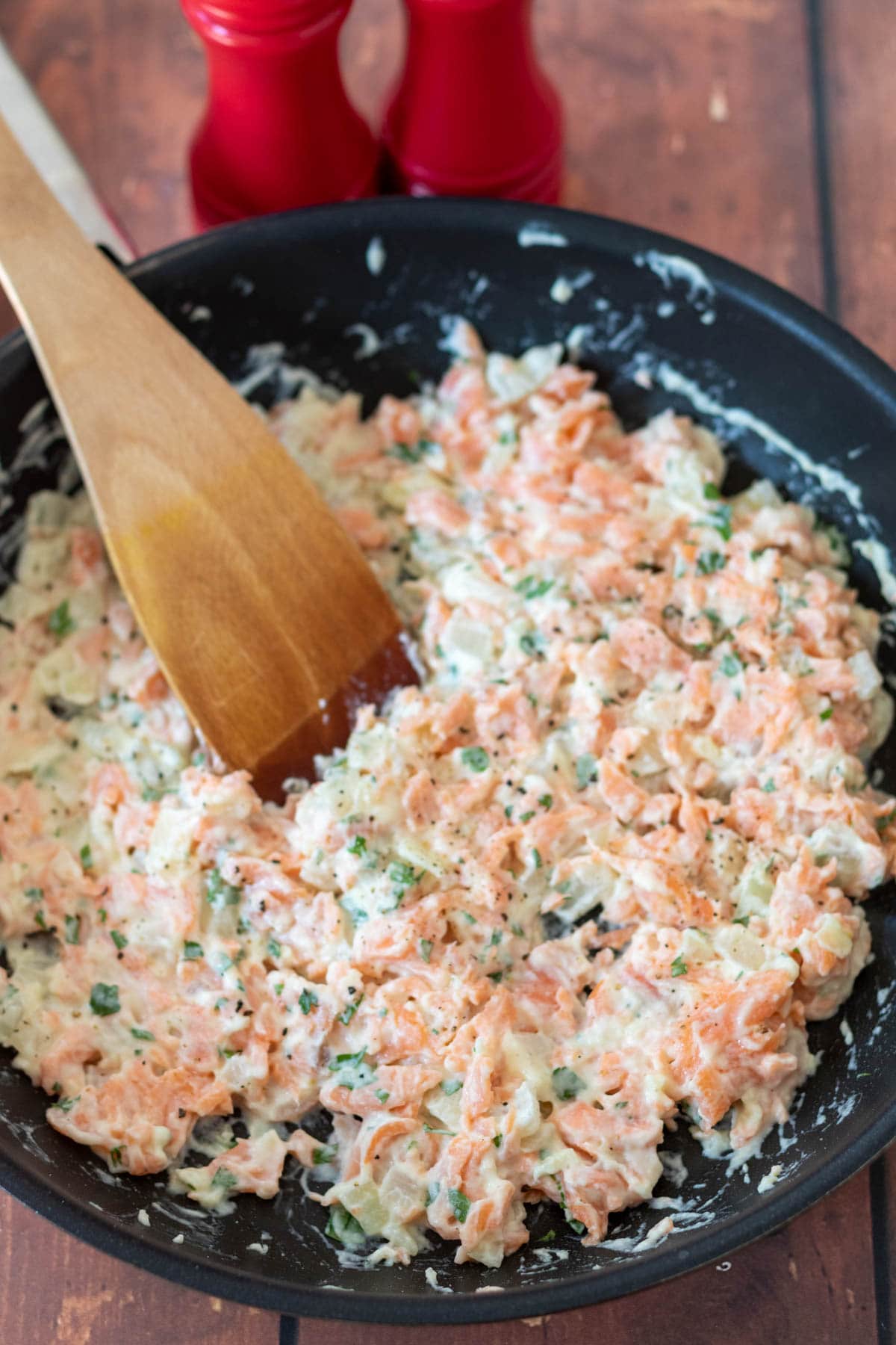 Stirring parsley into the healthy creamy salmon pasta and seasoning to taste.