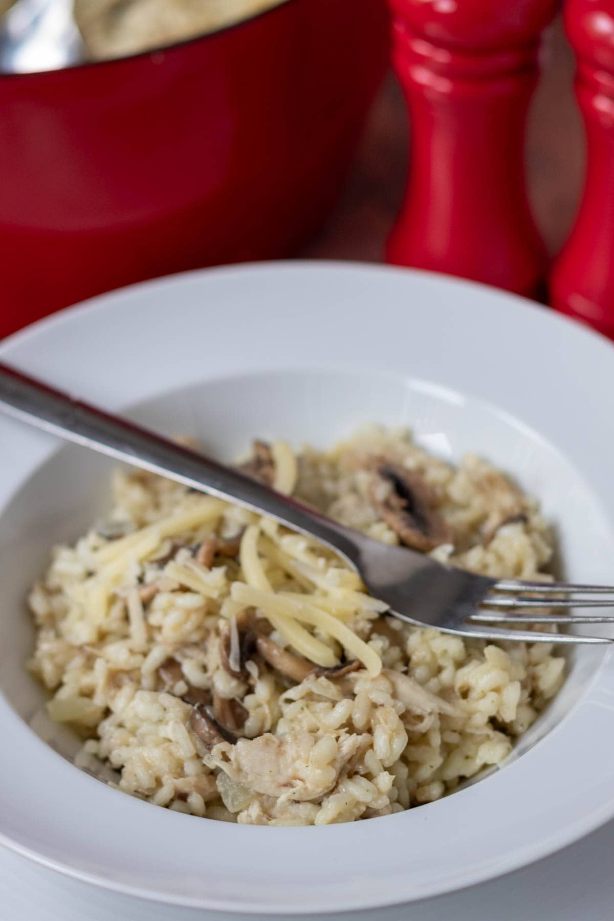 Close up of a serving of leftover turkey risotto in a large bowl with a fork in.