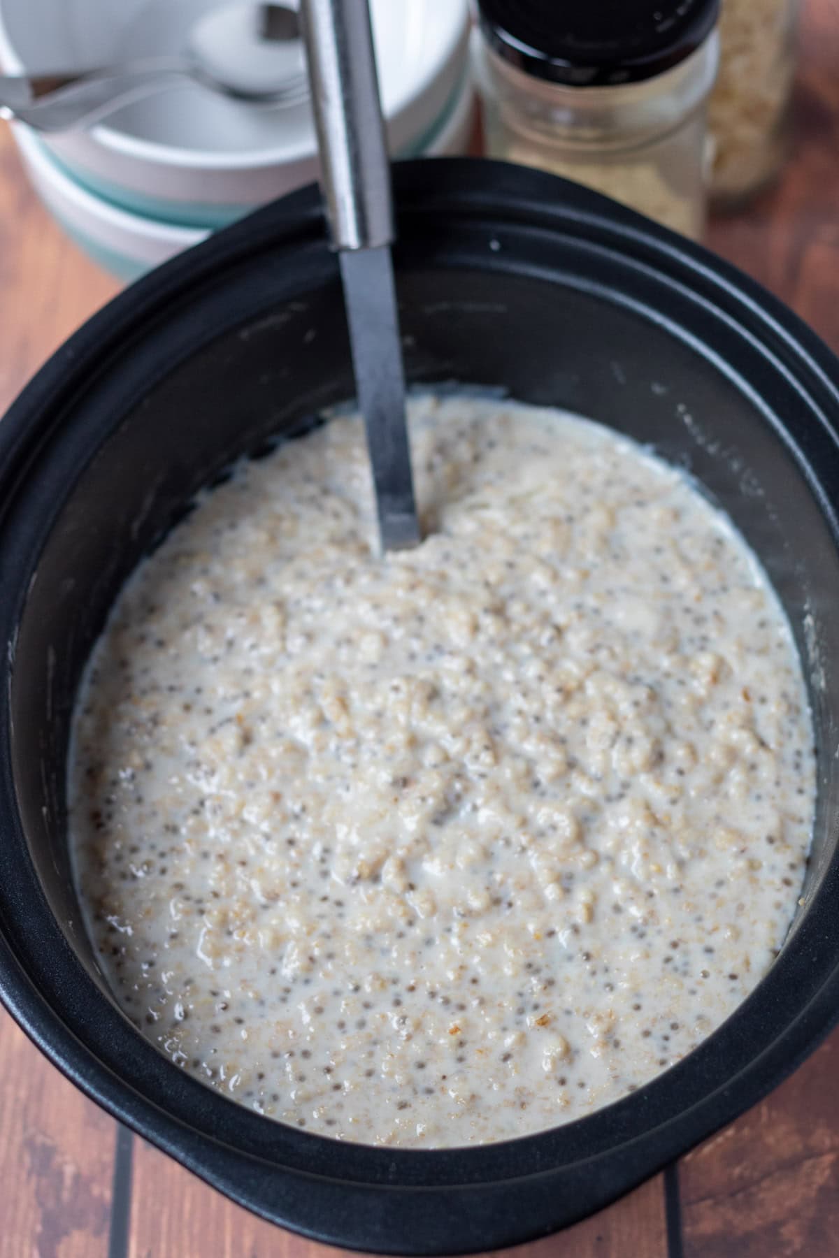 Cooked slow cooker banana porridge in slow cooker with a serving spoon. Ready to serve.