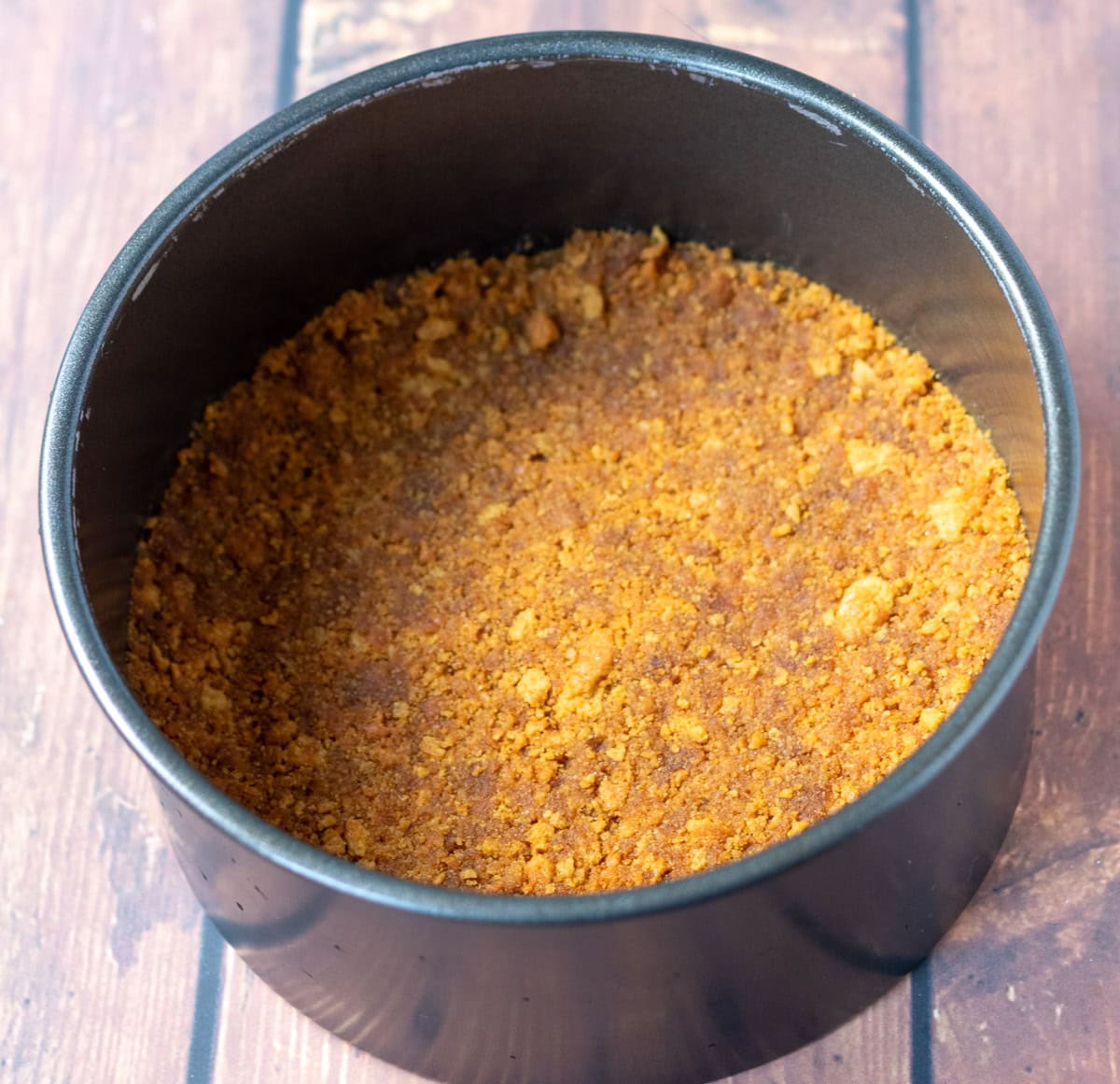 Biscuits pushed into bottom of linedcake tin to form cheesecake base.