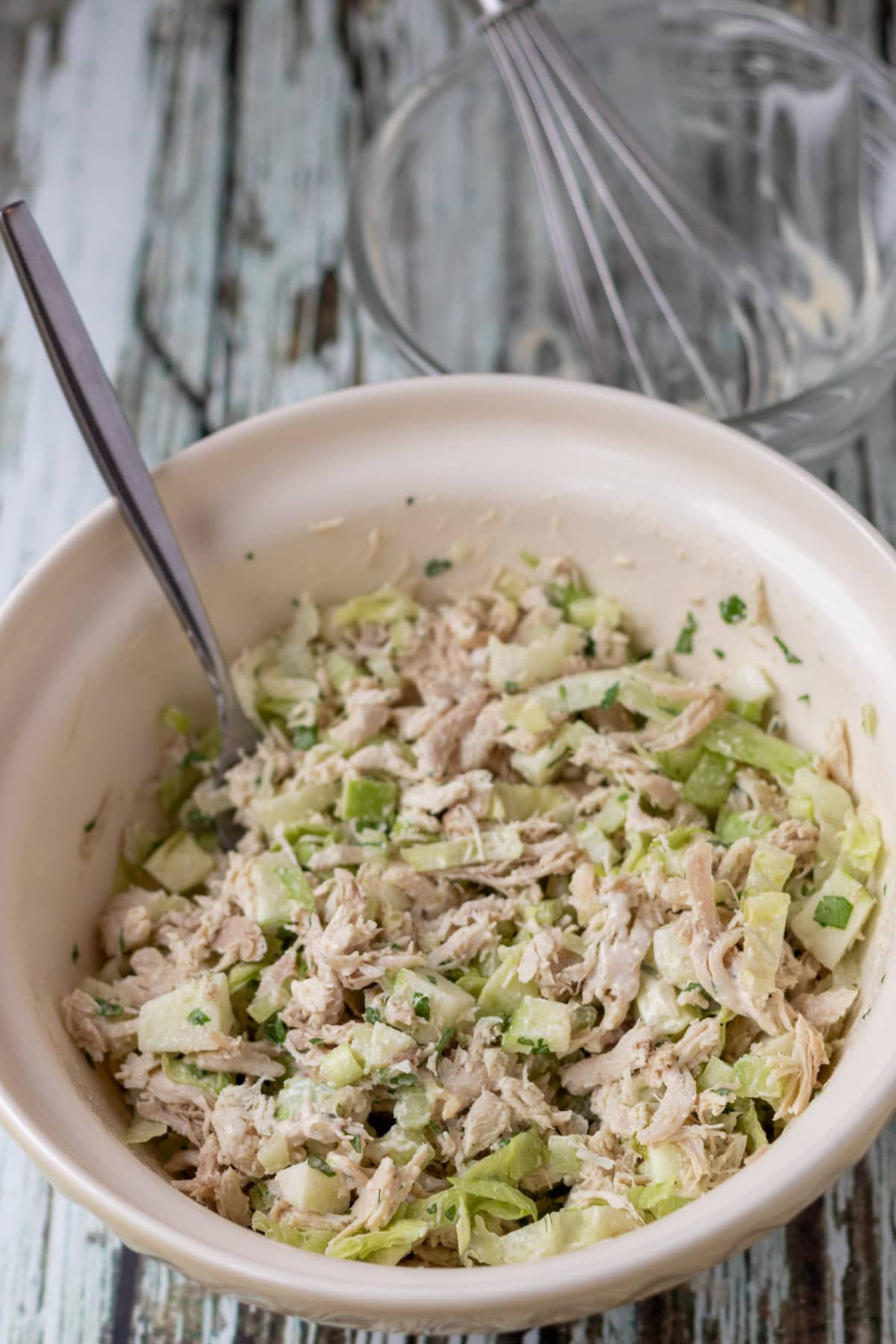 Turkey salad ingredients combined with dressing using a fork in a large mixing bowl.