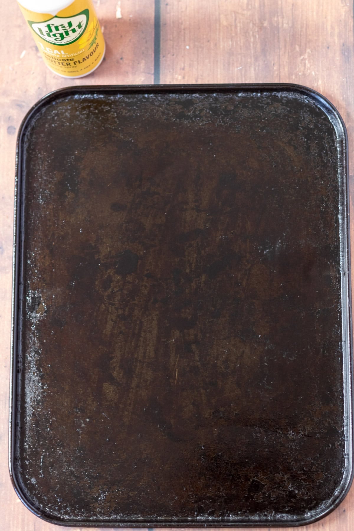 A baking tray sprayed with oil spray. Oil spray in the background.