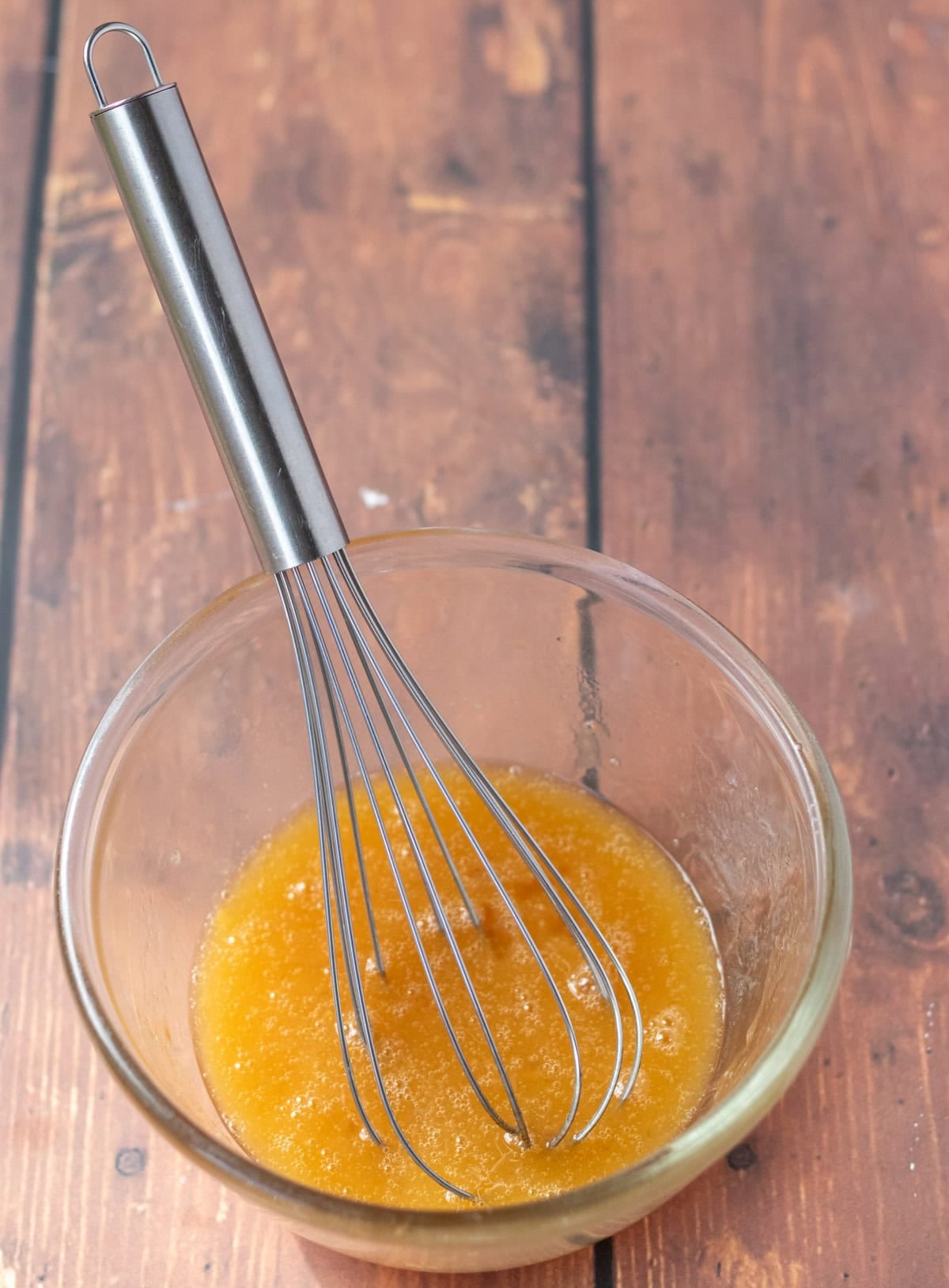 Honey , oil, egg and vanilla extract whisked together in a glass pyrex bowl with a whisk in.