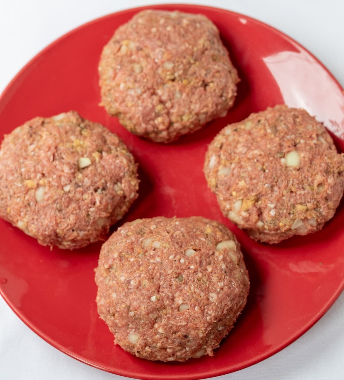 4 lamb burger patties on a plate.