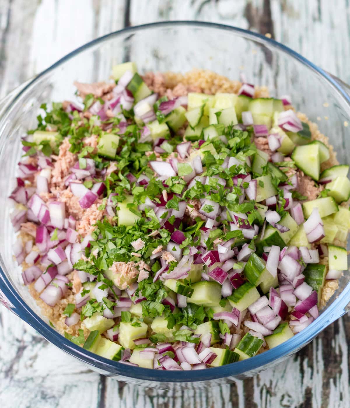 Tuna, red onion, cucumber and chopped parsley added to a bowl of quinoa.