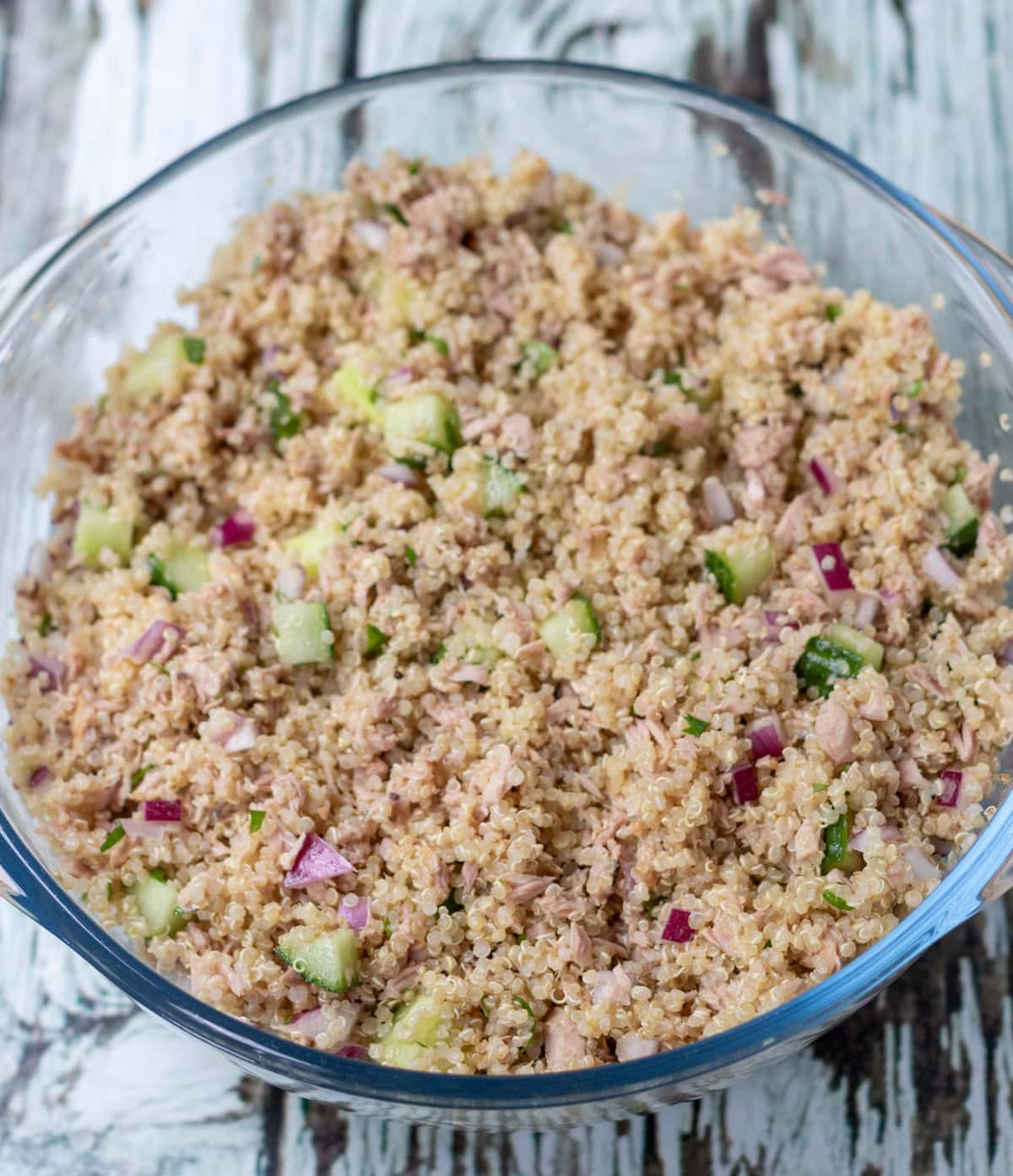 Tuna quinoa salad dressing combined with the other salad ingredients in a large bowl.