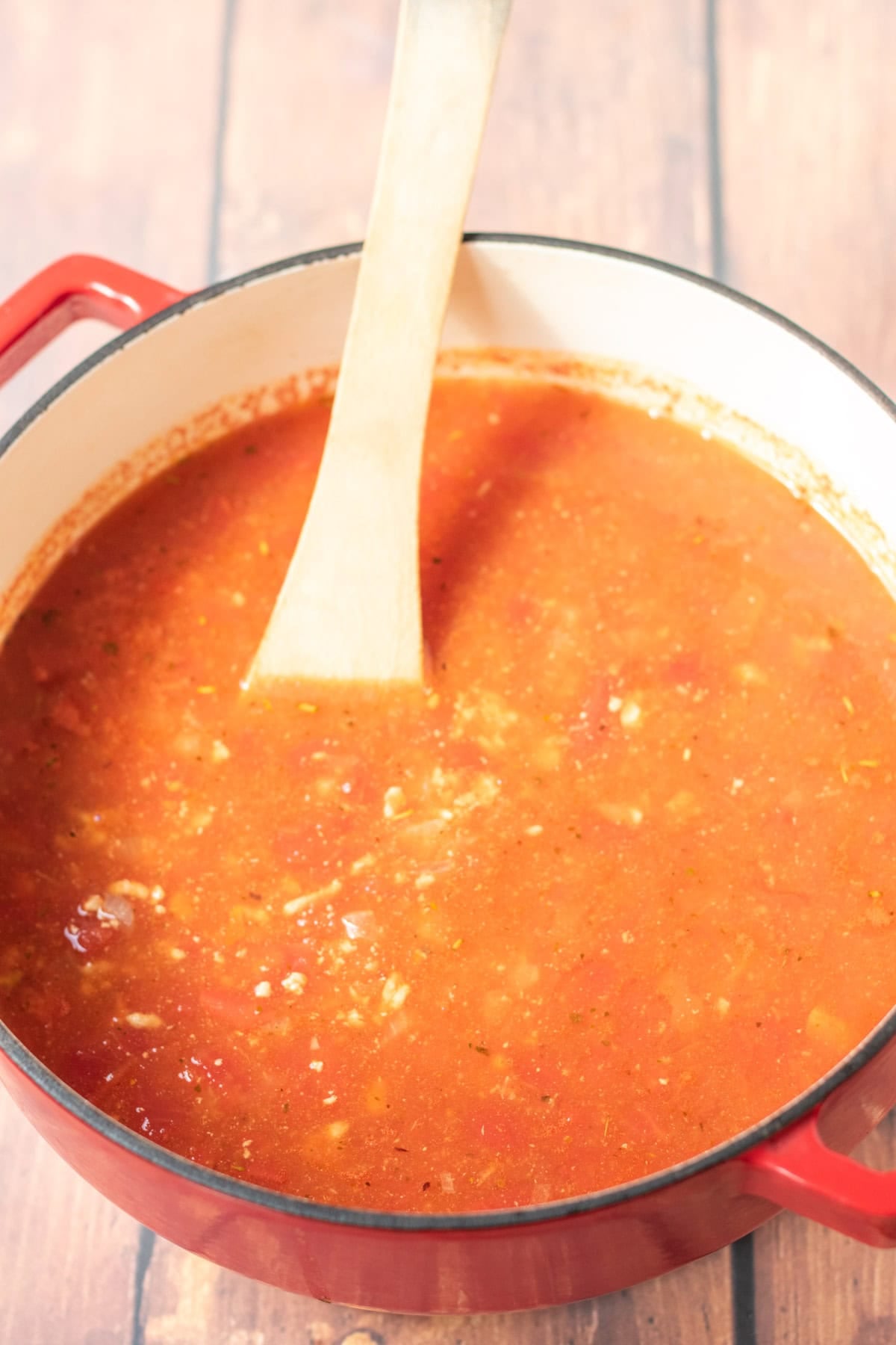 Chopped tomatoes and chicken stock added to the large casserole pot of turkey mince pasta.