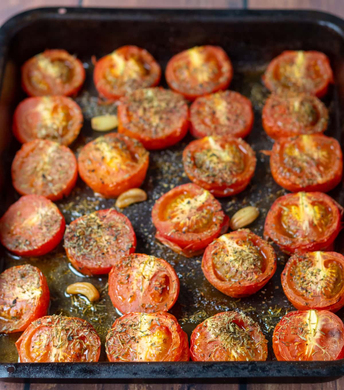 Tray of halved tomatoes cut side up roasted in over and removed after being roasted.